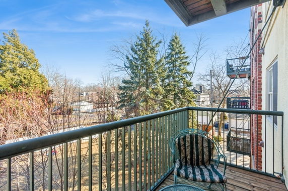 View from a balcony overlooking a residential area with trees and houses.