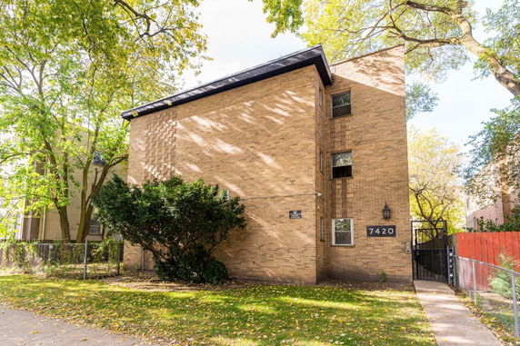 Front view of a multi-story brick building with a slanted roof.