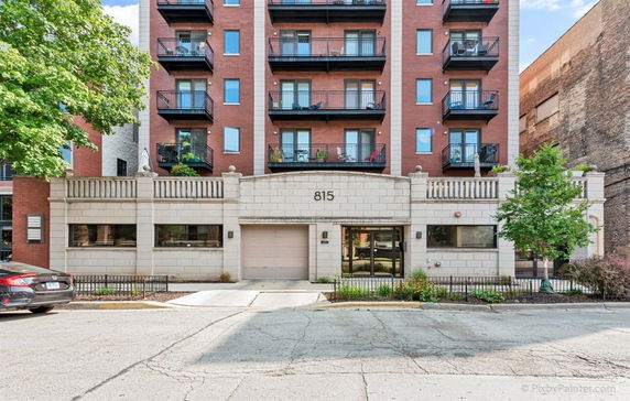 Front view of a multi-story building with balconies and a central entryway.