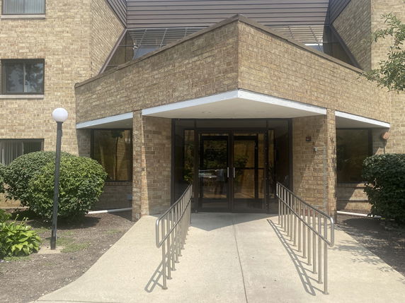 Front view of a brick building entrance with glass doors and a canopy.