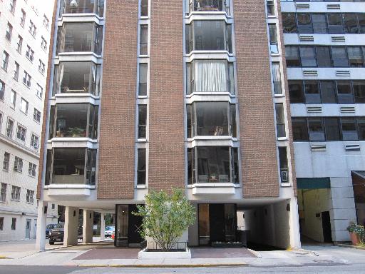 Front view of a mid-rise apartment building with brick facade and large windows.