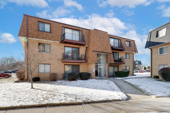 Front view of a multi-story brick apartment building with balconies.
