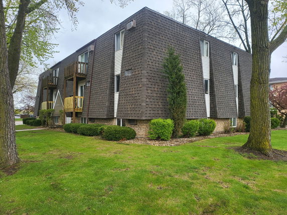 Front view of a multi-story building with balconies and shingle-style facade.