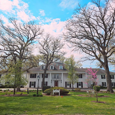 Front view of a large two-story house with a symmetrical design and a central balcony.