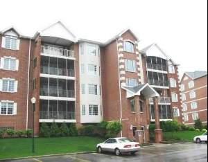 Front view of a multi-story residential building with brick exterior and balconies.
