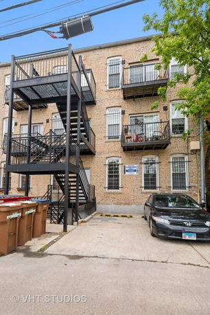 Rear view of a multi-story brick building with external metal staircases and balconies.