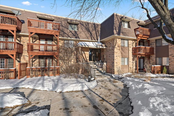 Front view of a multi-story brick apartment building with wooden balconies.