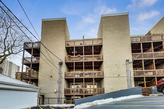 Rear view of a multi-story apartment building with wooden balconies.