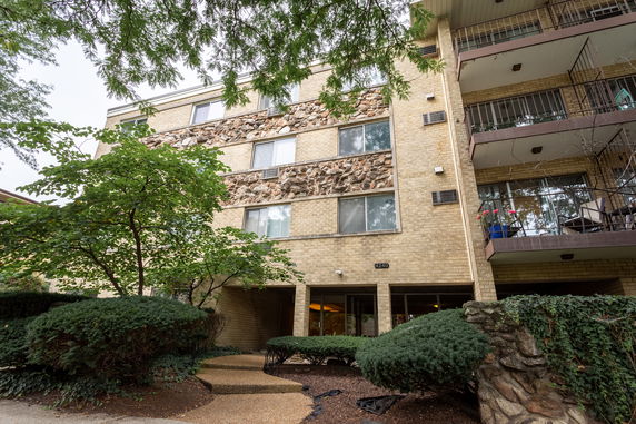 Front view of a multi-story apartment building with stone and brick facade.