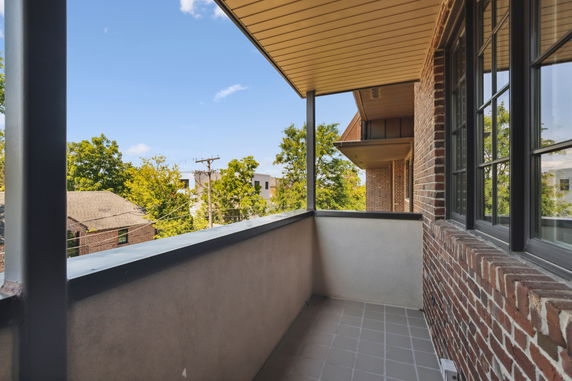 View from a balcony overlooking rooftops and trees.