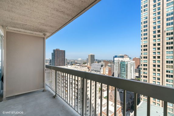 Panoramic view from a high-rise balcony overlooking a cityscape with tall buildings.