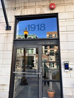 Front view of a building entrance with a glass door and large window above.