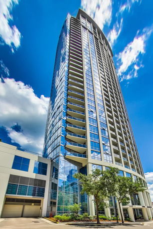 Front view of a tall modern apartment building with glass facade.