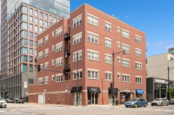 Front view of a multi-story brick building on a street corner.