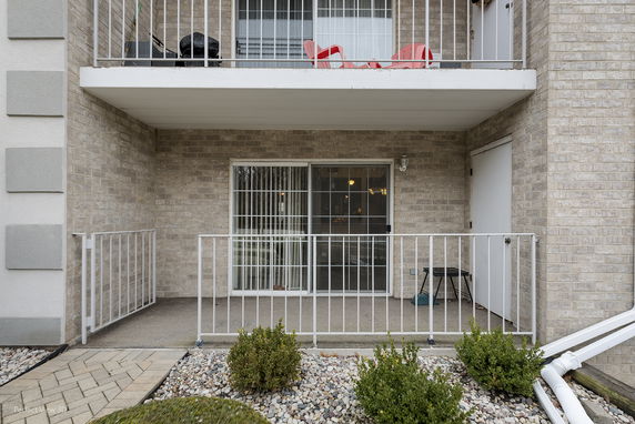 Front view of a multi-story building with balconies and sliding glass doors.