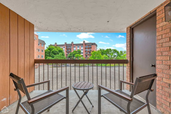 Balcony view overlooking an apartment complex and trees.