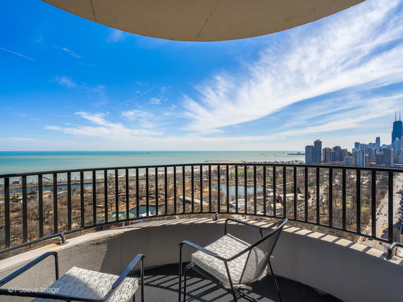 Wide-angle view of city skyline and lake from a curved balcony.