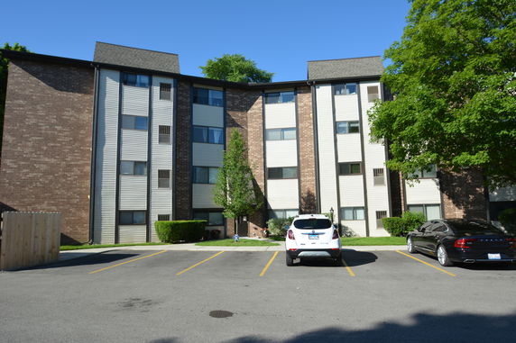 Front view of a multi-story apartment building with parking area.