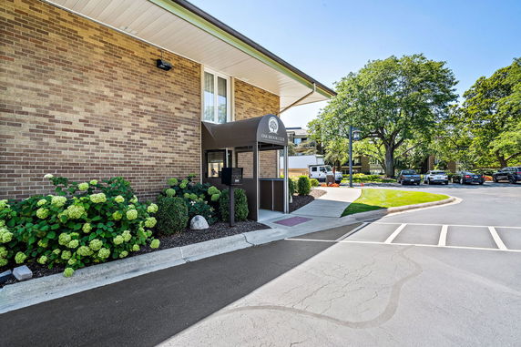 Front view of a brick building with an entrance canopy and surrounding greenery.