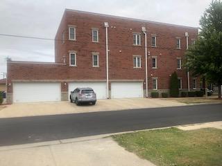 Front view of a three-story brick building with multiple garages.
