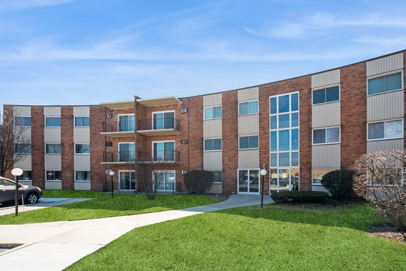 Front view of a multi-story apartment building with balconies and large windows.