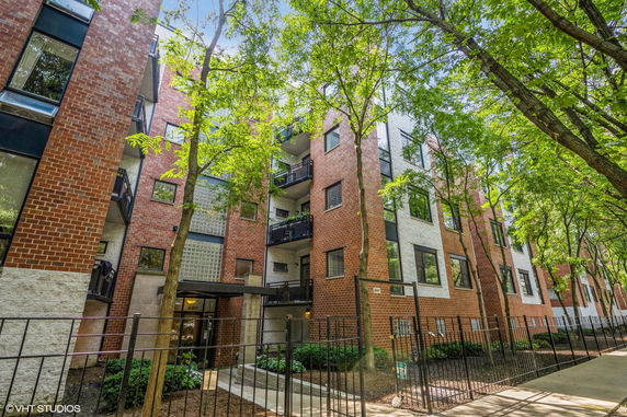 Front view of a multi-story brick apartment building with balconies.