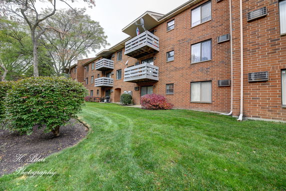 Front view of a brick apartment building with balconies and windows.
