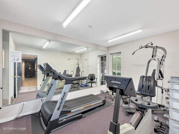 Indoor gym area with exercise equipment and large mirrors.