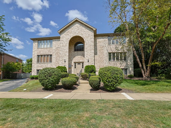 Front view of a two-story brick building with large windows and an arched entrance.