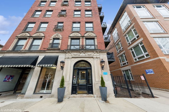 Front view of a multi-story brick building with decorative stonework and large windows.