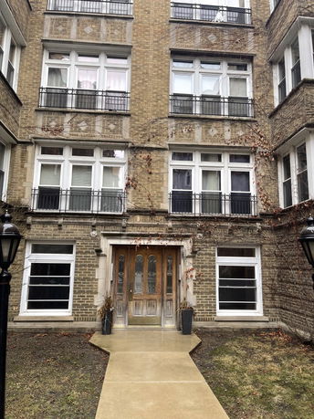 Front view of a multi-story brick building with large windows and a wooden entrance door.