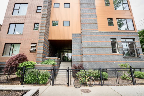 Front view of a modern multi-story building with brick and metal facade.