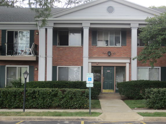 Front view of a two-story brick apartment building with columns and a central entrance.