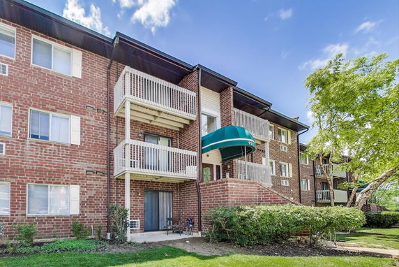 Front view of a multi-story brick apartment building with balconies.