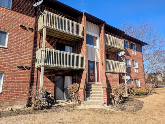 Front view of a multi-story brick apartment building with balconies.