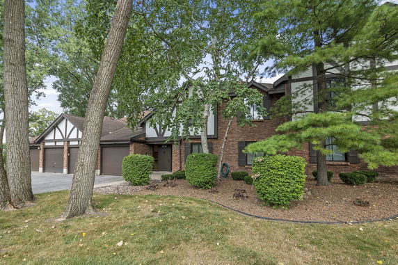 Front view of a multi-story house with a three-car garage and brick exterior.