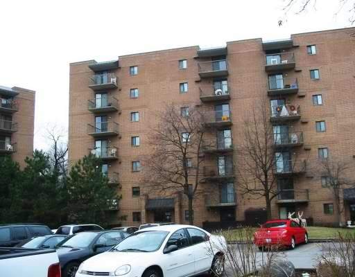Front view of a multi-story brick apartment building with balconies.
