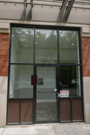 Front view of a commercial building with large glass windows and a door.