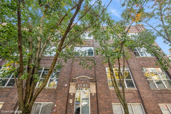 Front view of a multi-story brick building with large windows and a central entrance.