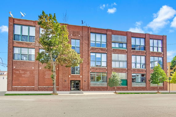 Front view of a multi-story brick building with large windows.