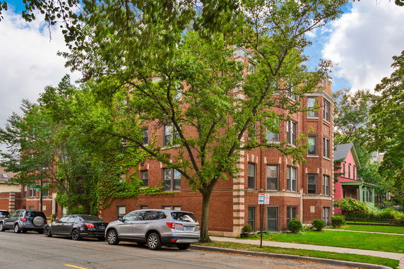 Front view of a multi-story brick building with corner windows.