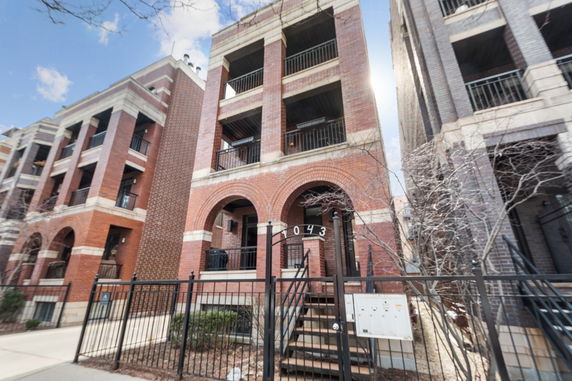 Front view of a multi-story brick building with balconies and arched entrances.