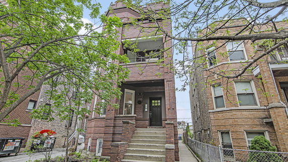 Front view of a brick residential building with a staircase leading to the entrance.