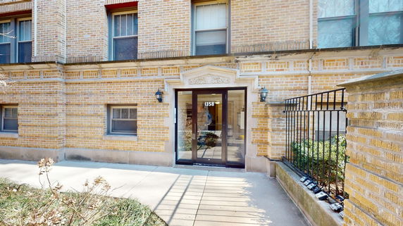 Front view of a brick building entrance with glass doors.