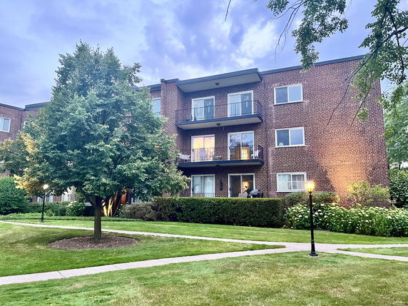 Front view of a three-story brick residential building with balconies.