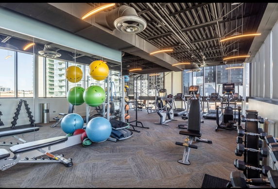 Indoor gym with exercise equipment, including weights and cardio machines.