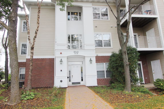 Front view of a multi-story residential building with balconies and brick facade.