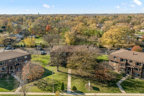 Aerial view of residential buildings surrounded by trees and open spaces.