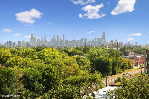 Wide angle view of a cityscape with skyscrapers and greenery in the foreground.