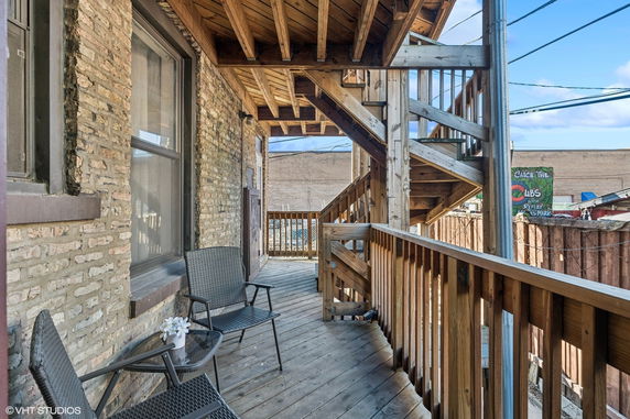 Outdoor wooden balcony area with seating and staircase